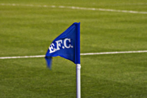 Everton Corner Flag which is a Royal Blue triangle on a white pole with the letters EFC on it blowing in the wind to signify the winds of change blowing through Goodison Park